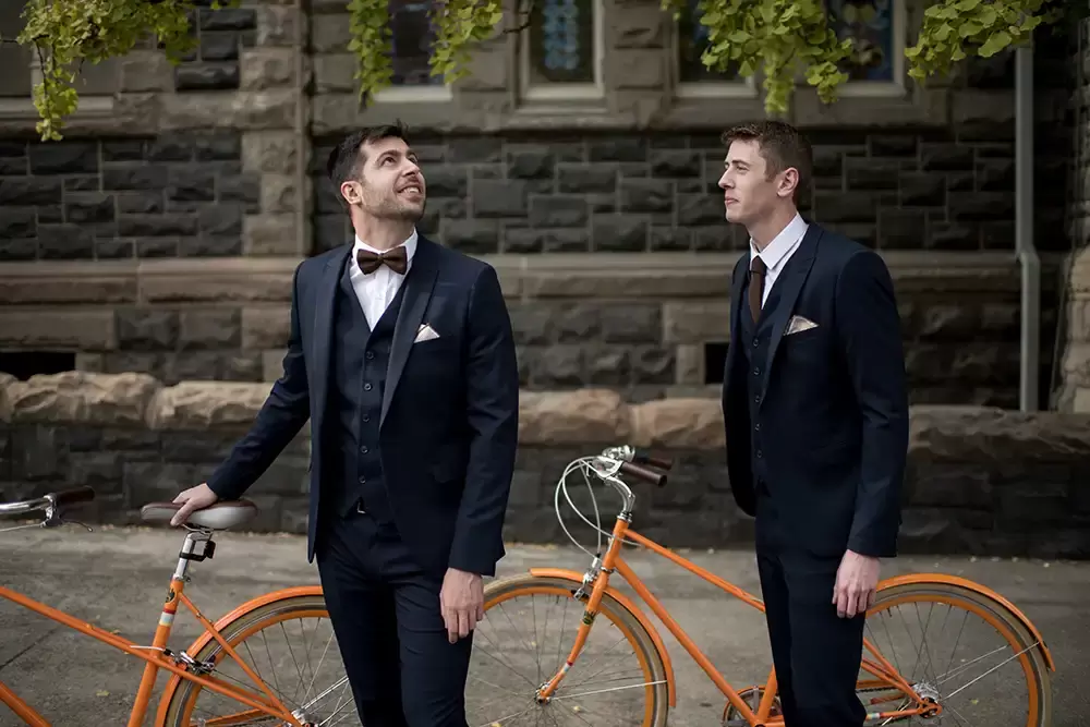 Portland Wedding Photographer Robert Knapp Photographs two grooms on bikes around portland. One Looks to the other. He is noticing the beauty of the moment. 