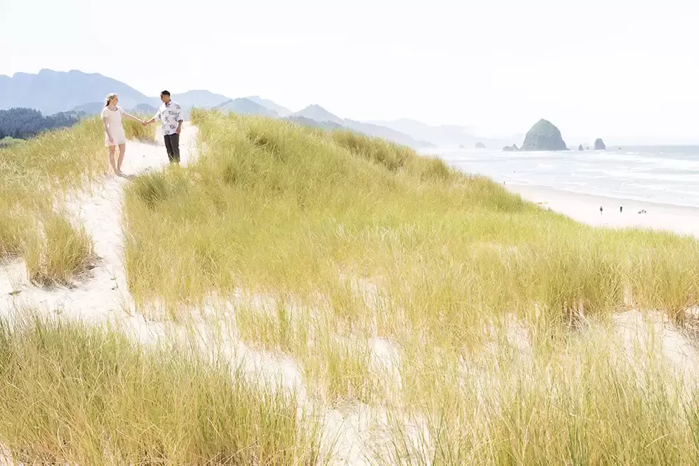 a couple walk on a path in the dunes during Cannon Beach Engagement Photos With Photographer Robert Knapp