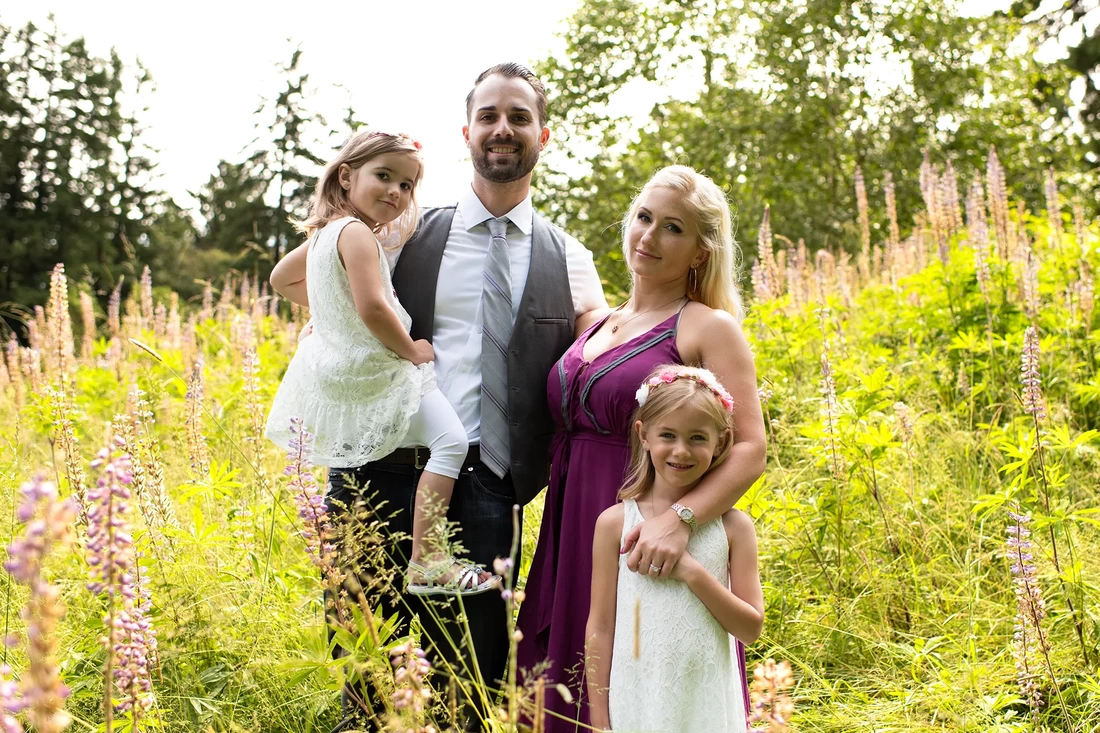 A family stands in a meadow of wildflowers in the sun Garden Photoshoot with Robert Knapp one of the highly sought after Family Photographers Portland has to offer