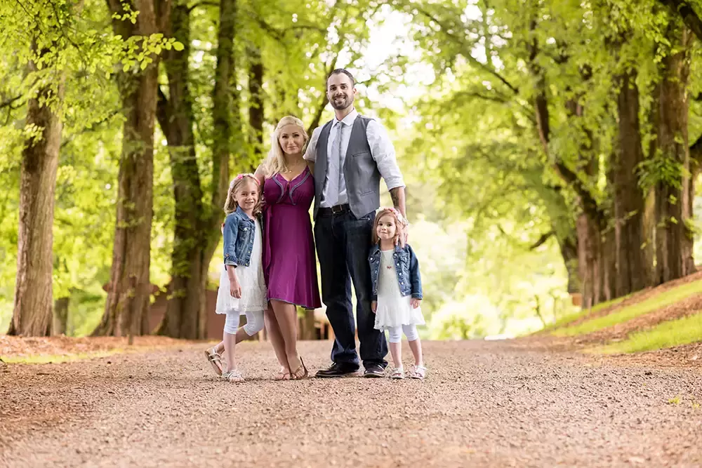 a family poses standing in the middle of a dirt road Garden Photoshoot with Robert Knapp one of the highly sought after Family Photographers Portland has to offer