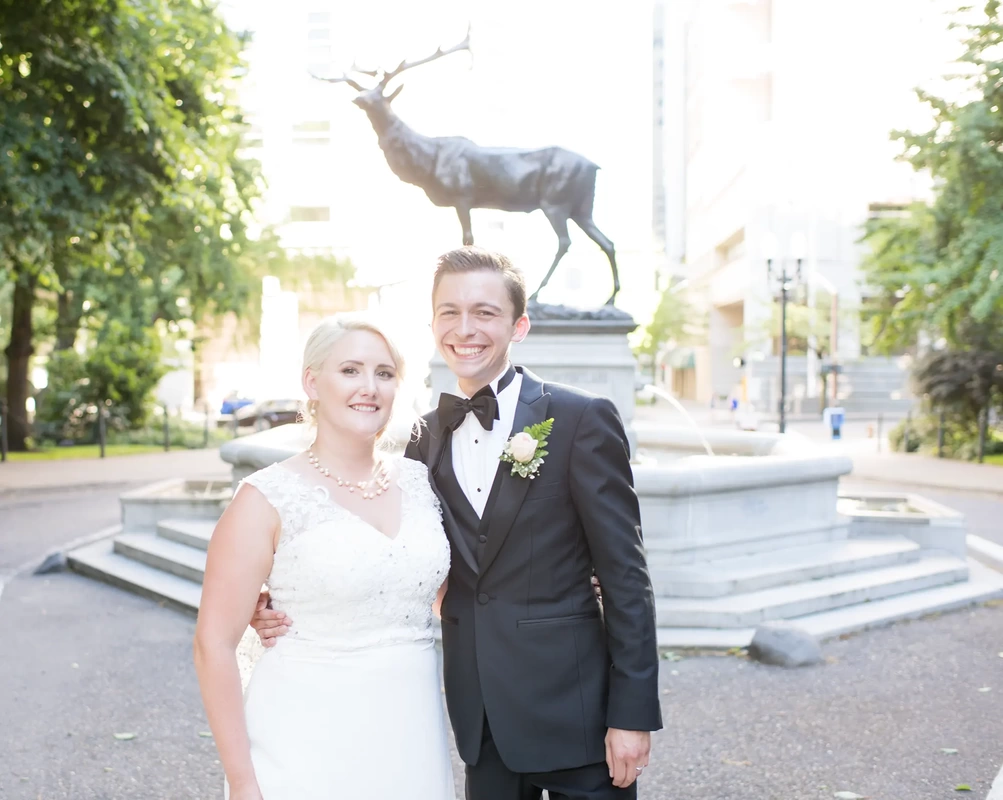 Hotel Deluxe Wedding in Portland Oregon by Photographer Robert Knapp a bronze stag over a fountain in the background, the bride and groom look to the camera