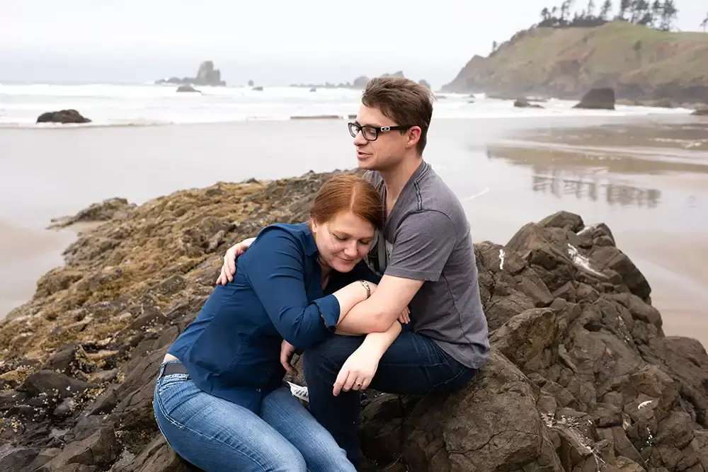 a woman cuddles into a mans chest on a rock by the sea shore Modern Art Photograph 
Engagement Photography Portland Oregon