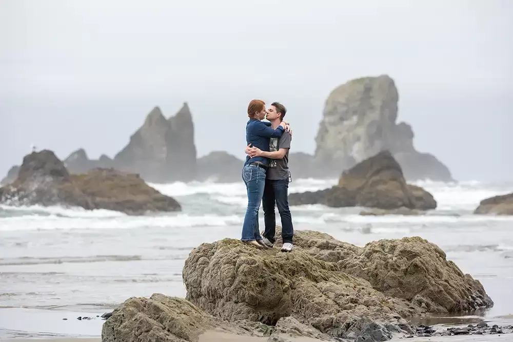 A couple kisses on a rock as the waves have them stranded for a moment. Modern Art Photograph 
Engagement Photography Portland Oregon