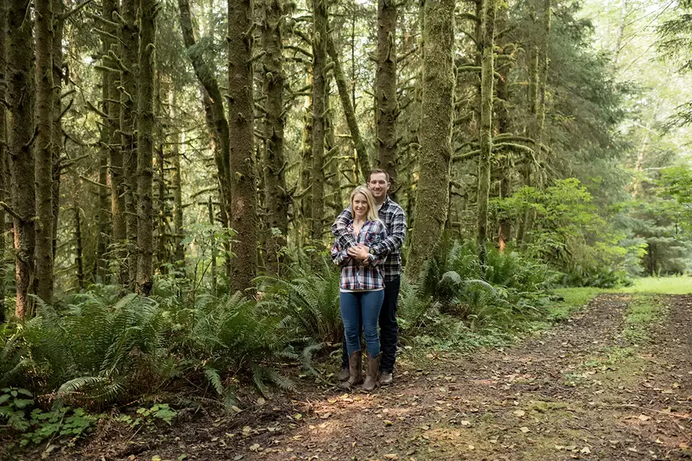 a couple stands in the trees together Oregon Coast Engagement Photos 
With 
Modern Art Photograph