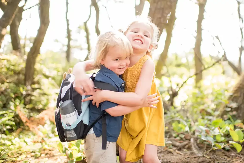 warm hugs from sister to brother standing in the forest together   Family Pictures Beach Theme with Portland Family Photographer Robert Knapp